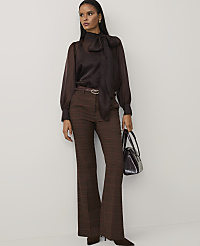 A woman wearing a brown pussy-bow blouse and plaid trousers stands against a plain white background. carousel Product Image 3