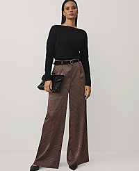 A woman wearing a black sweater and brown plaid wide-leg trousers stands against a plain, light-colored background. carousel Product Image 1