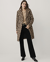 A woman wearing a leopard print coat, beige sweater, and black flared trousers stands against a plain white background. carousel Product Image 1
