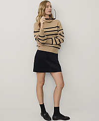 A blonde woman wearing a tan striped turtleneck and a black mini skirt stands against a plain white background. carousel Product Image 3