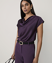 A woman wearing a purple satin cowl-neck top and matching trousers with a black belt stands against a plain, light-colored background. carousel Product Image 1