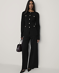 A woman wearing a black buttoned blazer and wide-leg trousers holds a burgundy handbag against a plain white background. carousel Product Image 3