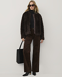 A woman wearing a brown faux-fur jacket, leopard print trousers, and sunglasses stands against a plain white background. carousel Product Image 1