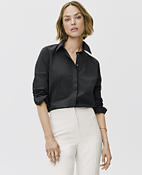 A woman wearing a black button-down shirt and white trousers stands against a plain light gray background. carousel Product Image 3