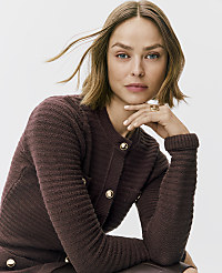 A woman with blonde hair wearing a textured burgundy cardigan poses against a plain white background. carousel Product Image 2