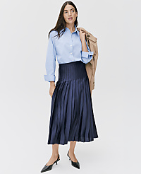 A woman wearing a light blue button-down shirt, a navy pleated midi skirt, and black pointed heels stands against a plain white background. carousel Product Image 4