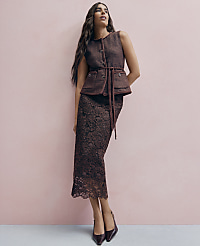 A woman wearing a brown tweed vest and lace skirt stands against a solid pink wall. carousel Product Image 4