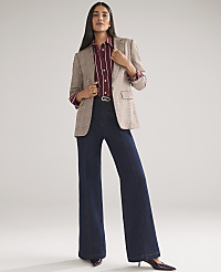 A woman wearing a plaid blazer, striped shirt, and wide-leg dark denim jeans stands against a plain, light gray background. carousel Product Image 1