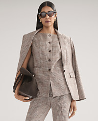 A woman wearing a brown plaid suit and sunglasses holds a dark brown handbag against a plain light gray background. carousel Product Image 1