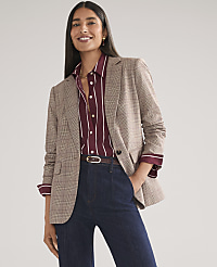 A smiling woman wearing a plaid blazer, striped maroon shirt, and dark blue jeans stands against a plain light gray background. carousel Product Image 3