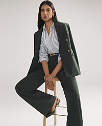 A woman wearing a dark green power suit and a striped shirt stands against a plain white background. carousel Product Image 4