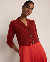 A woman wearing a red knit cardigan and a matching red satin skirt poses against a plain, neutral-toned background. carousel Product Image 1