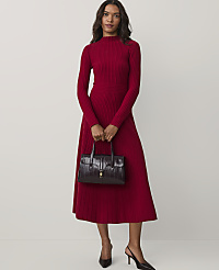 A woman wearing a long-sleeved red ribbed dress and black heels holds a dark burgundy handbag against a plain white background. carousel Product Image 1