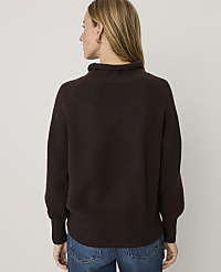 A woman wearing a dark brown knit sweater and blue jeans stands with her back to the camera against a plain white background. carousel Product Image 2