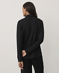 A woman wearing a black long-sleeved ribbed top and black pants stands with her back to the camera against a plain light gray background. carousel Product Image 2
