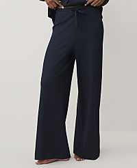 A person wears navy blue wide-leg ribbed trousers against a plain, light-colored background. carousel Product Image 1