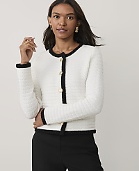 A woman wearing a white textured jacket with black trim and black trousers stands against a plain light gray background. carousel Product Image 1
