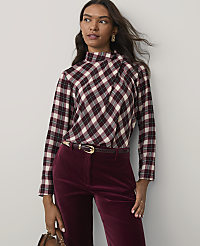 A woman wearing a plaid top and burgundy velvet trousers stands against a plain light gray background. carousel Product Image 1