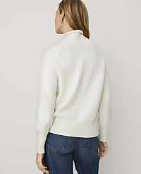 A woman wearing a white fuzzy sweater and blue jeans stands with her back to the camera against a plain light gray background. carousel Product Image 2