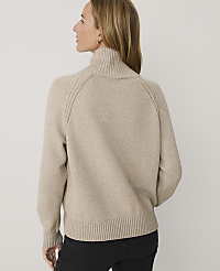 A woman wearing a beige turtleneck sweater and black pants stands against a plain white background. carousel Product Image 2