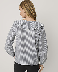 A woman wearing a blue and white striped blouse with a ruffled collar stands against a plain light gray background. carousel Product Image 2
