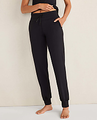 A person wears olive green joggers and a matching top against a plain, neutral-colored wall. carousel Product Image 1