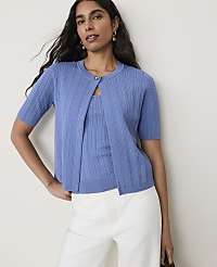 A woman in a blue cardigan and matching top stands against a plain, light-colored background. carousel Product Image 1