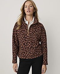 A woman wearing a leopard-print quarter-zip pullover and black pants stands against a plain, light-colored background. carousel Product Image 1