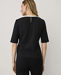 A woman wearing a black short-sleeved top and black pants stands with her back to the camera against a plain light gray background. carousel Product Image 2