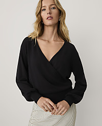 A blonde woman wearing a black wrap-style top and a patterned skirt stands against a plain white background. carousel Product Image 1