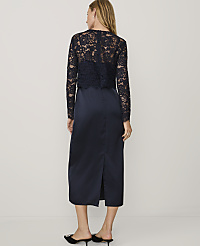 A woman stands with her back to the camera wearing a navy blue lace top and satin skirt against a plain white background. carousel Product Image 2