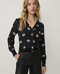 A woman wearing a black floral blouse and black leather pants stands against a plain, light-colored background. carousel Product Image 1