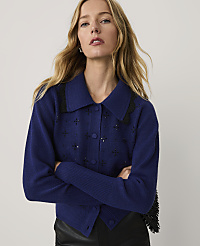 A blonde woman wearing a blue embellished cardigan and black leather pants stands against a plain white background. carousel Product Image 1
