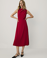 A woman wearing a sleeveless red midi dress and black pointed-toe heels stands against a plain, light-colored background. carousel Product Image 1