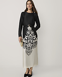 A woman wearing a black and white patterned dress and black heels stands against a plain white background. carousel Product Image 3