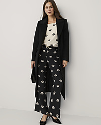 A woman wearing a black coat, a floral top, and matching floral trousers stands against a plain white background. carousel Product Image 1