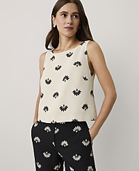 A woman wearing a cream floral top and black floral trousers stands against a plain light gray background. carousel Product Image 1