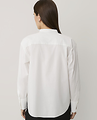A woman wearing a white long-sleeved shirt and black trousers stands with her back to the camera against a plain light gray background. carousel Product Image 2