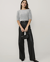 A woman wearing a shimmering silver top and black faux-leather trousers stands against a plain white background. carousel Product Image 3