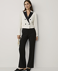 A woman wearing a white and black tuxedo jacket with black flared trousers stands against a plain white wall. carousel Product Image 3