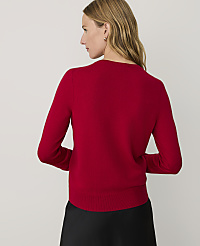 A woman wearing a red sweater and black skirt stands with her back to the camera against a plain light gray background. carousel Product Image 2