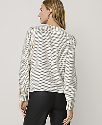 A woman wearing a white polka-dot blouse and black trousers stands with her back to the camera against a plain light gray background. carousel Product Image 2