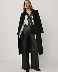 A woman wearing a black coat, a polka-dot blouse with lace detailing, and wide-leg leather trousers stands against a plain white background. carousel Product Image 3