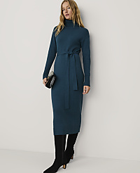 A woman wearing a long teal knit dress and black boots stands against a plain white background. carousel Product Image 1