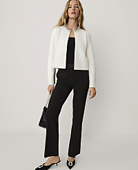 A woman wearing a white embellished jacket and black trousers stands against a plain, light-colored background. carousel Product Image 3