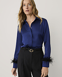 A woman wearing a royal blue satin shirt with feather cuffs and black trousers stands against a plain light gray background. carousel Product Image 1