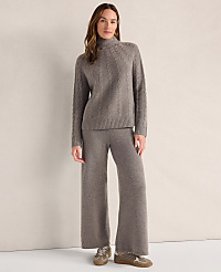 A woman wearing a grey cable-knit sweater and matching wide-leg trousers stands against a plain, neutral-colored background. carousel Product Image 1