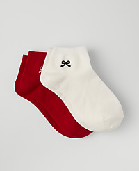 Three pairs of socks, one white with a small black bow and two red, are stacked against a plain light gray background. carousel Product Image 1