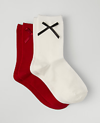 Three socks, one white and two red, each adorned with a small bow, are layered on a plain light gray background. carousel Product Image 1