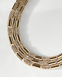 A gold-toned chain with sparkling diamond-encrusted links curves across a plain white background. carousel Product Image 2